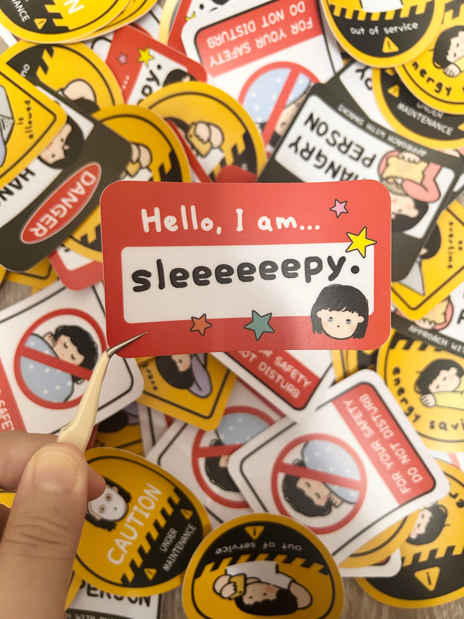 Vinyl Sticker with humorous text 'Hello, I am... sleeeeeepy.' text held over a collection of themed stickers.