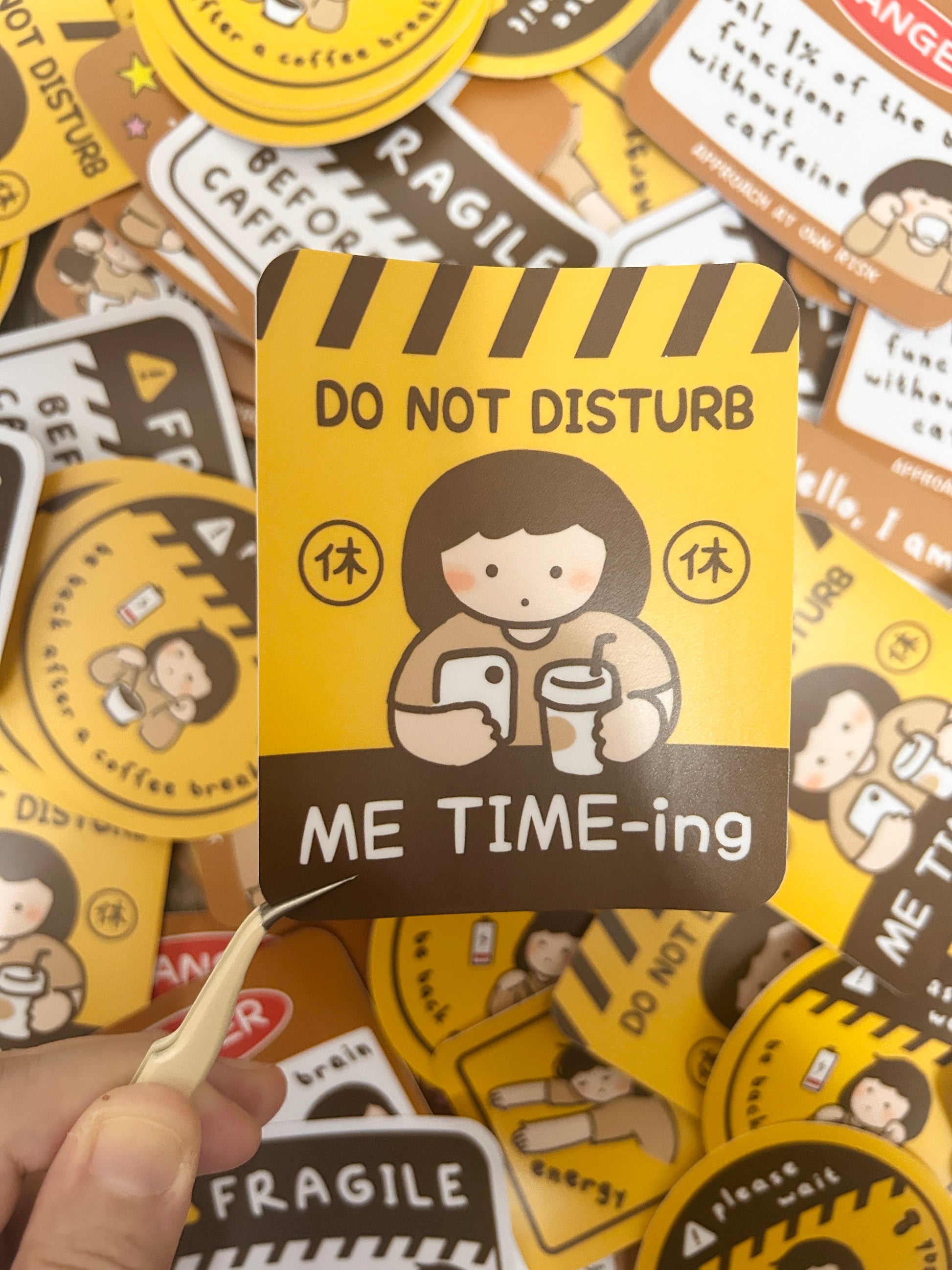 Vinyl sticker with 'Do Not Disturb Me Time-ing' design held by a hand against a background of similar stickers.